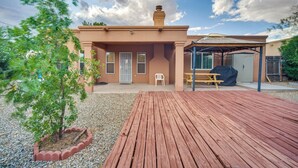 Una casa con terraza de madera, un patio techado y un jardín pequeño.