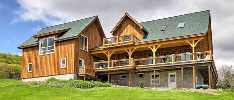 A large wooden house with multiple levels, a balcony, and a covered porch.