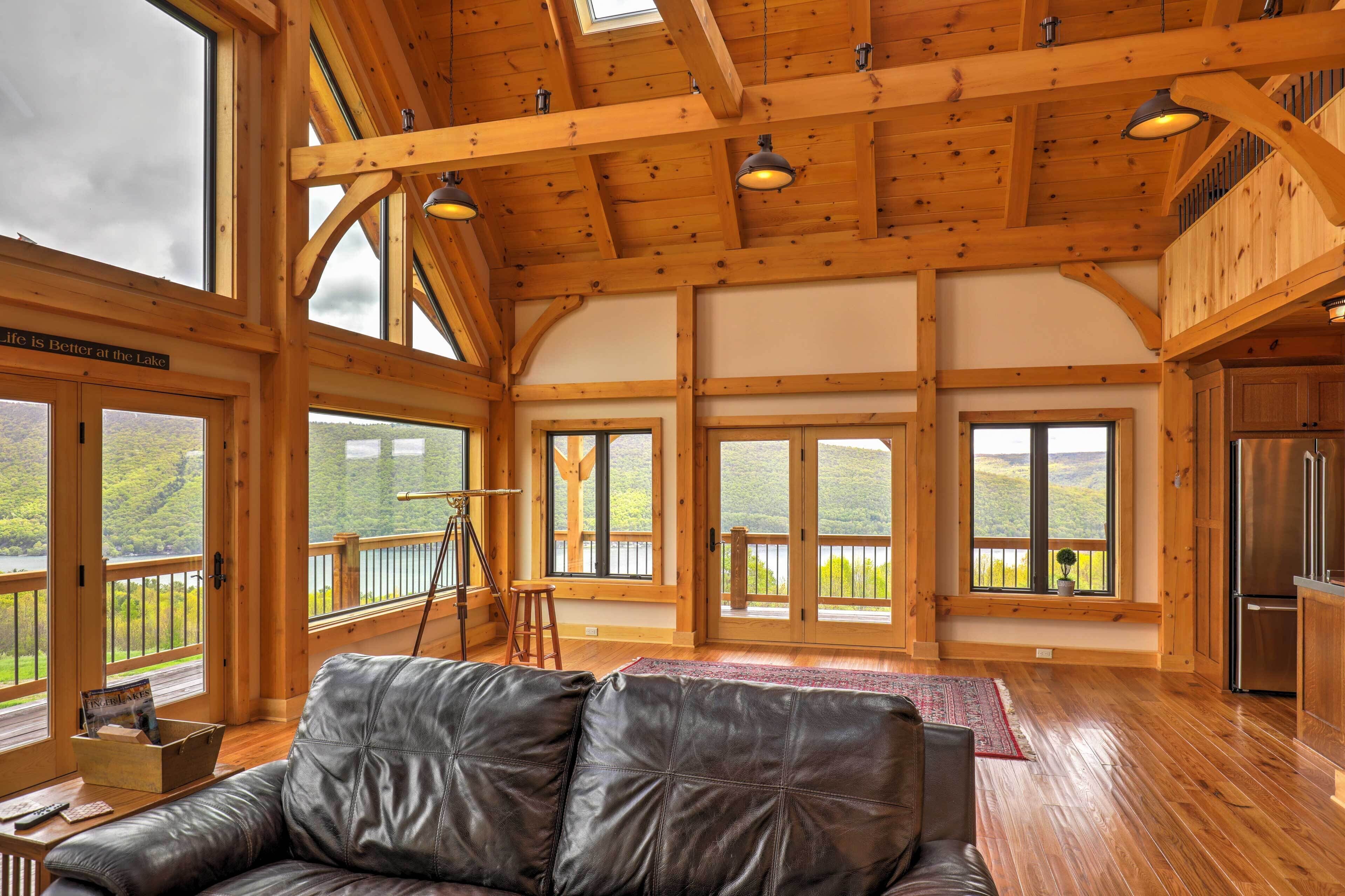 A spacious room with large windows, a wooden ceiling, and a black leather couch.
