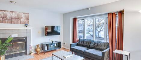 A modern living room with a fireplace, a sofa, a coffee table, and a television.