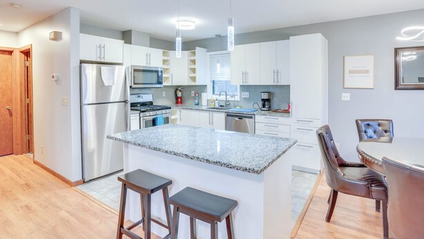 A modern kitchen with white cabinets, stainless steel appliances, and a granite countertop.