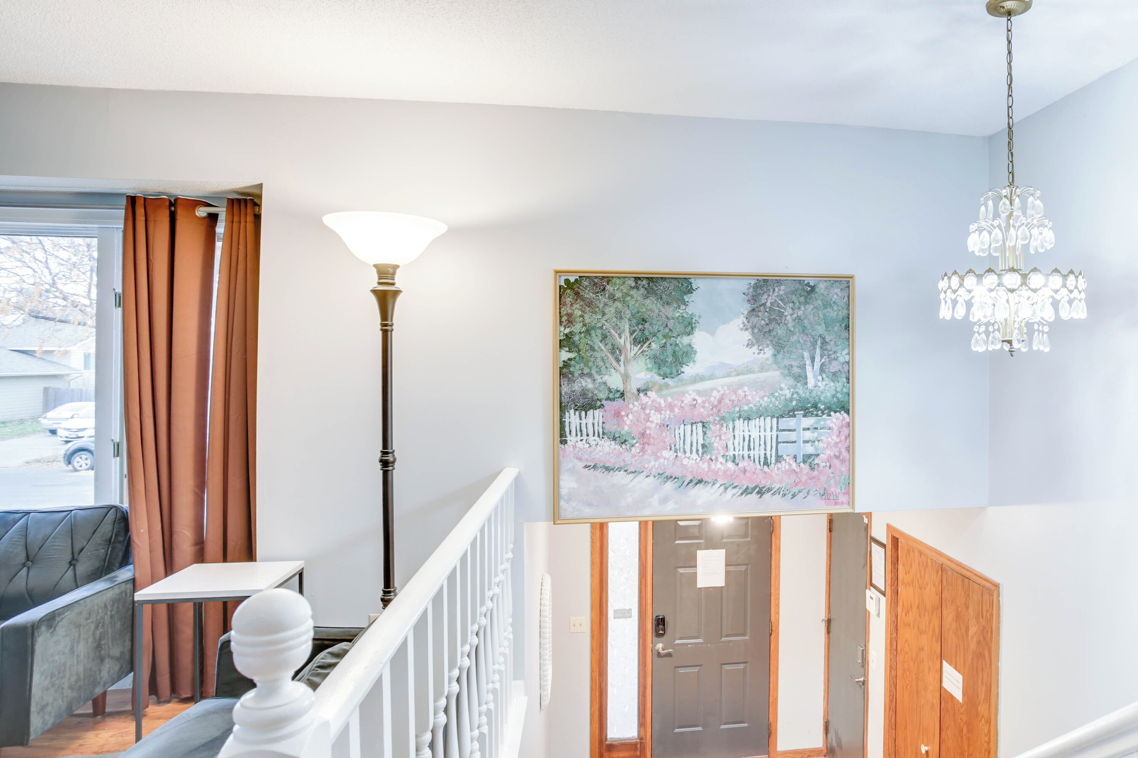 Vestíbulo de hotel con una escalera, un comedor y un cuadro de una escena de jardín.