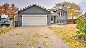 A residential house with a garage, a front yard with fallen leaves, and a wooden fence.