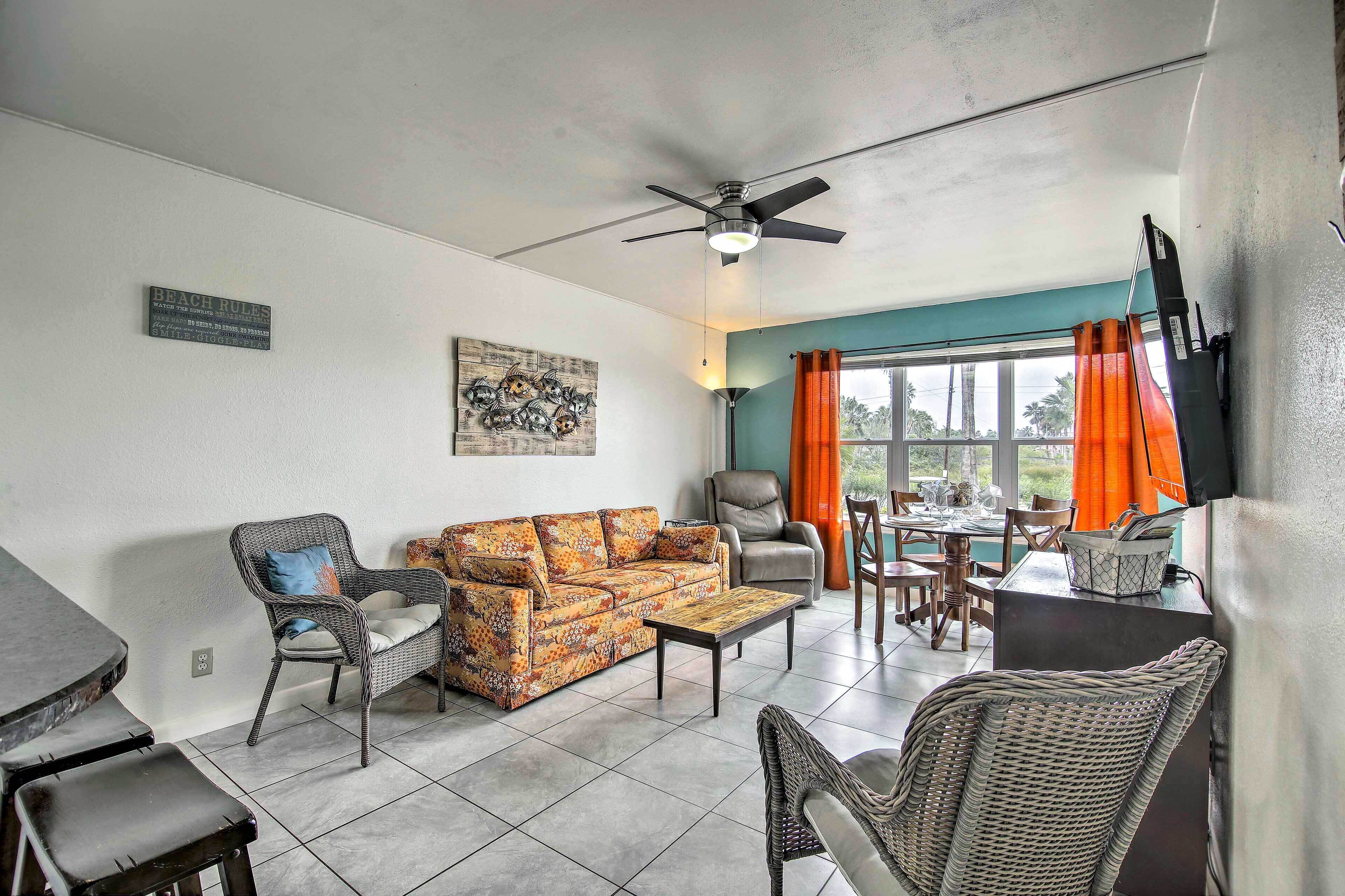 A living room with a sofa, chairs, a coffee table, a ceiling fan, and a dining area with a table and chairs.