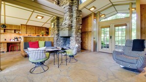 A cozy interior with a stone fireplace, wooden furniture, and a stone floor. - Tranquil Mid-century Modern Cottage w/ Forest View (Cherokee Village)
