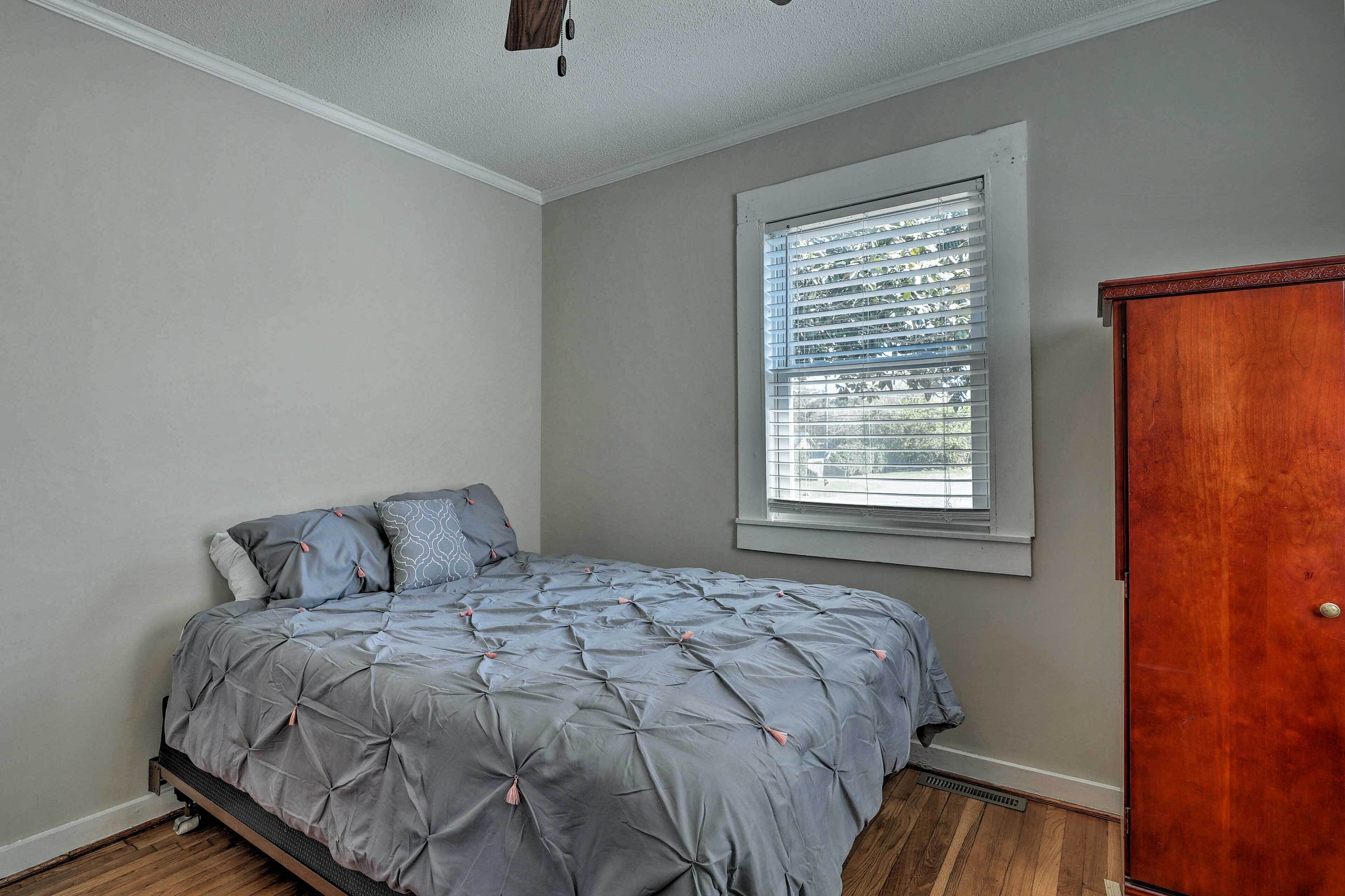 Un dormitorio con cama, ventana con persianas, armario de madera y radiador.