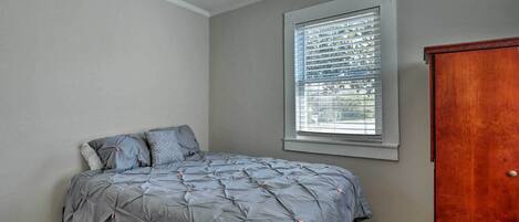 Un dormitorio con cama, ventana con persianas, armario de madera y radiador.