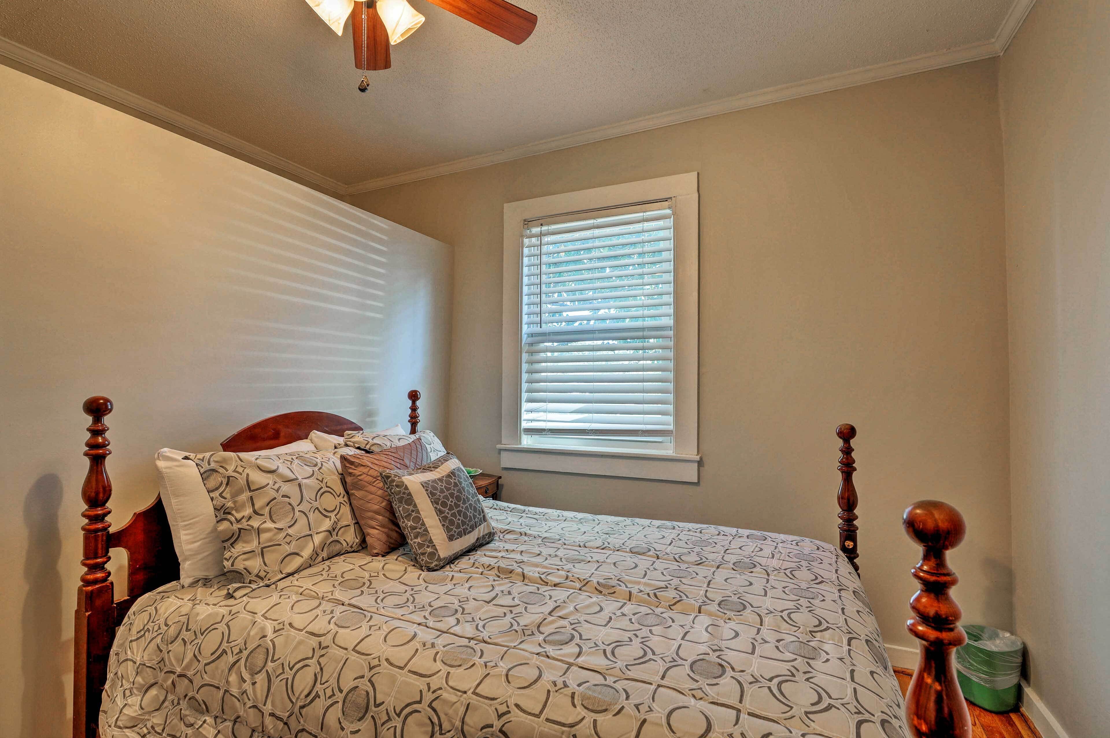 A bedroom with a bed, wooden headboard, and a window with blinds.