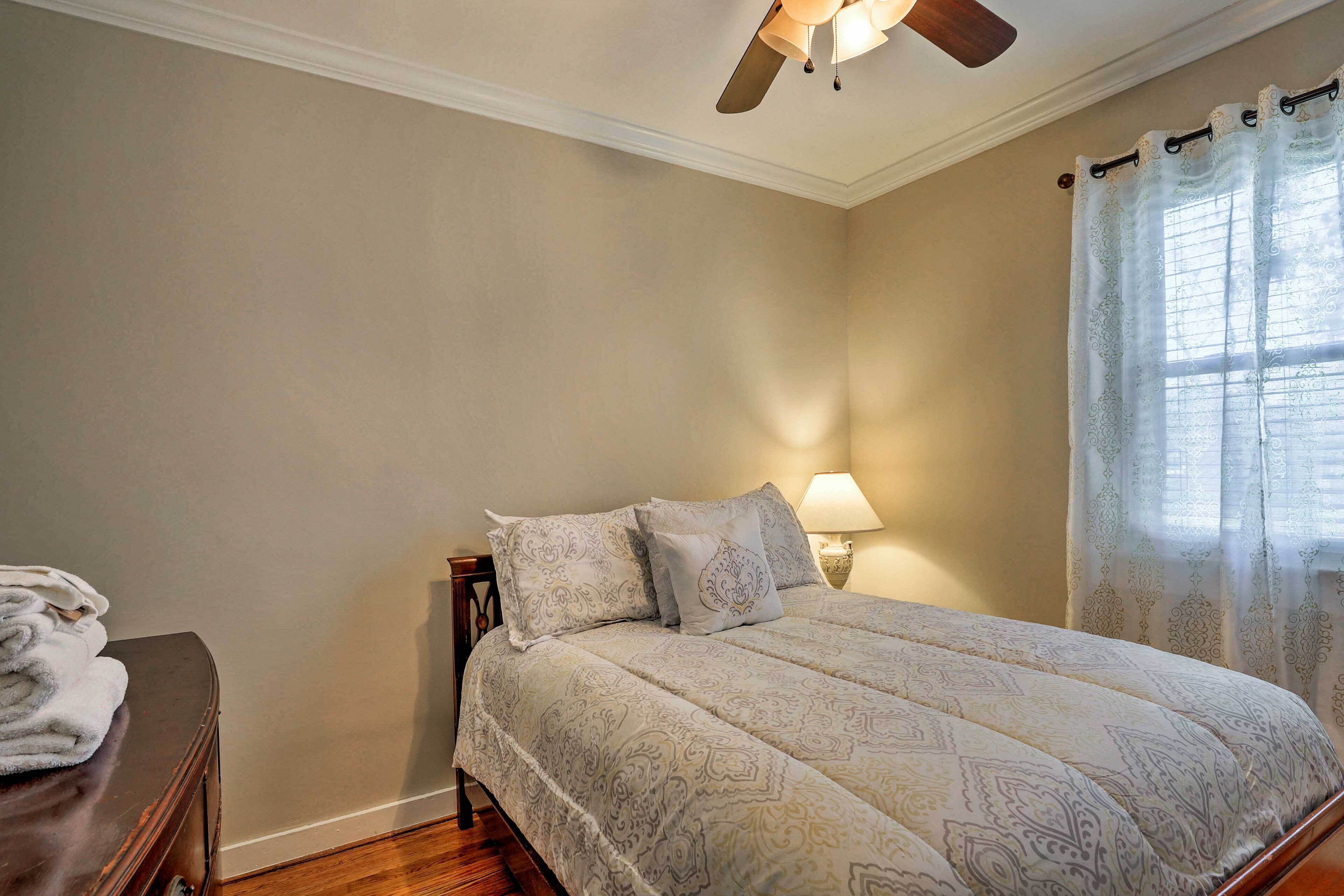 A bedroom with a bed, a nightstand, a lamp, and a ceiling fan.