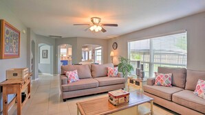 A spacious living room with a beige sofa, a wooden coffee table, and a ceiling fan.
