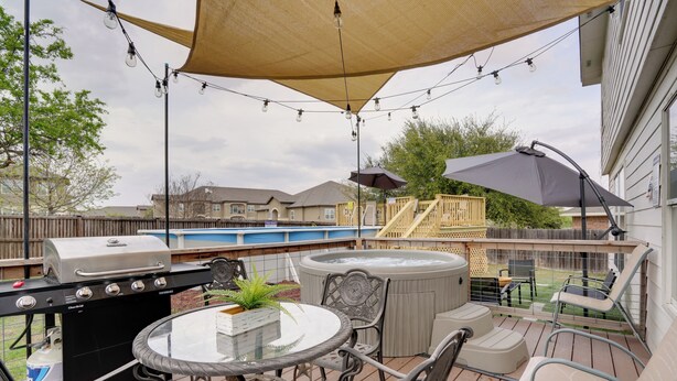 An outdoor patio with a grill, hot tub, and seating area.