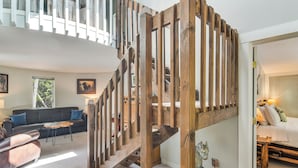 Un intérieur moderne avec un escalier en colimaçon en bois, un salon avec un canapé et une table basse, et une chambre à coucher avec un lit et une table de chevet.