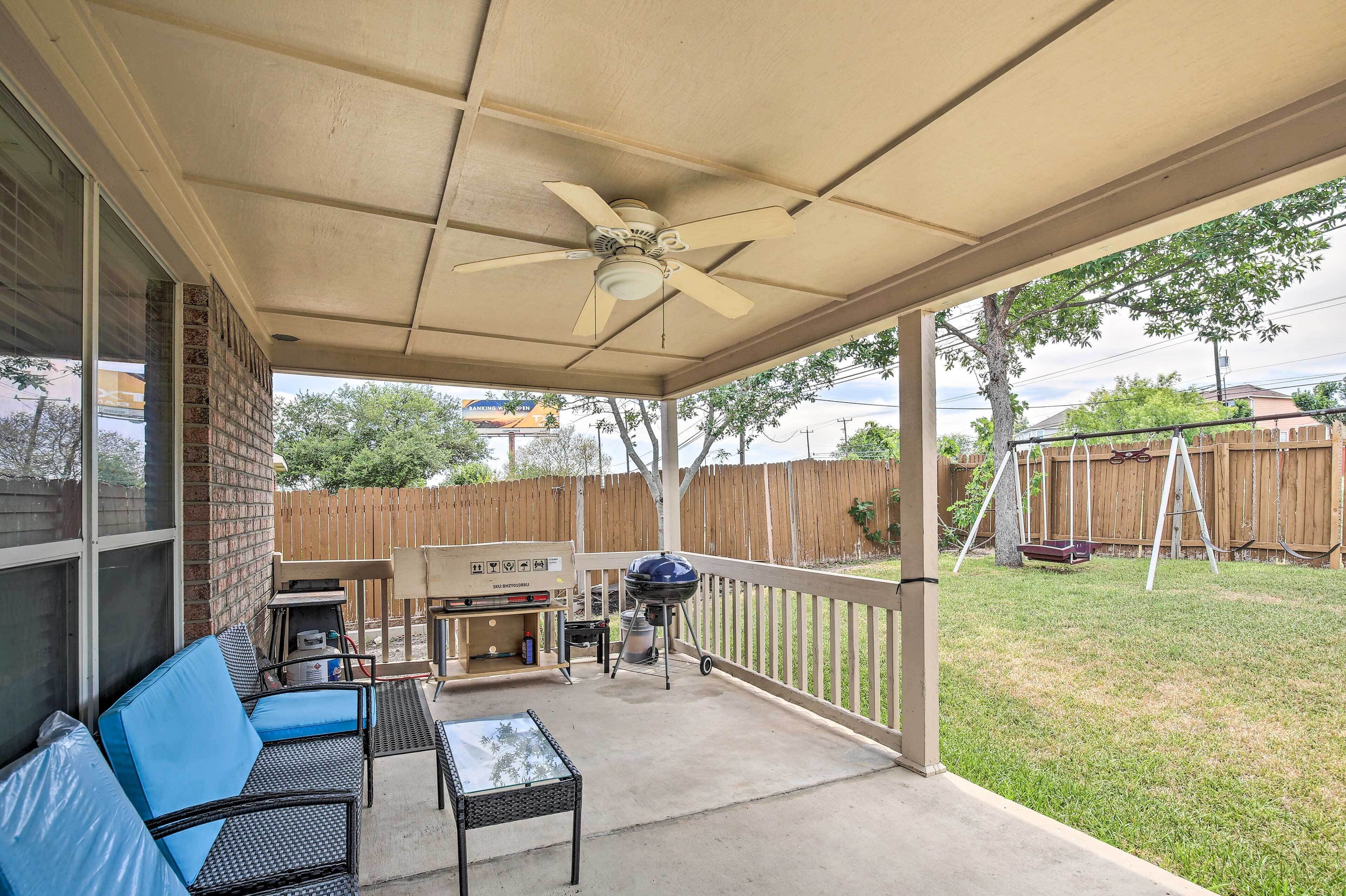 A covered patio area with a ceiling fan, a grill, outdoor furniture, and a view of the backyard.