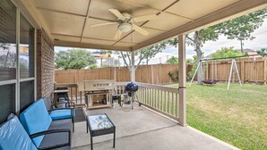 A covered patio with a ceiling fan, a grill, a sofa, and a table.