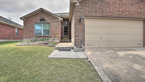 A two-story brick house with a garage, a front yard, and a small porch.