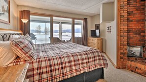 A bedroom with a large bed, a wooden dresser, a TV, and a brick fireplace. - Mtn Views, Ground Floor: Rec Path and Lake Access (Dillon)