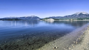 A calm lake with clear water reflecting the sky and mountains in the background. - Mtn Views, Ground Floor: Rec Path and Lake Access (Dillon)