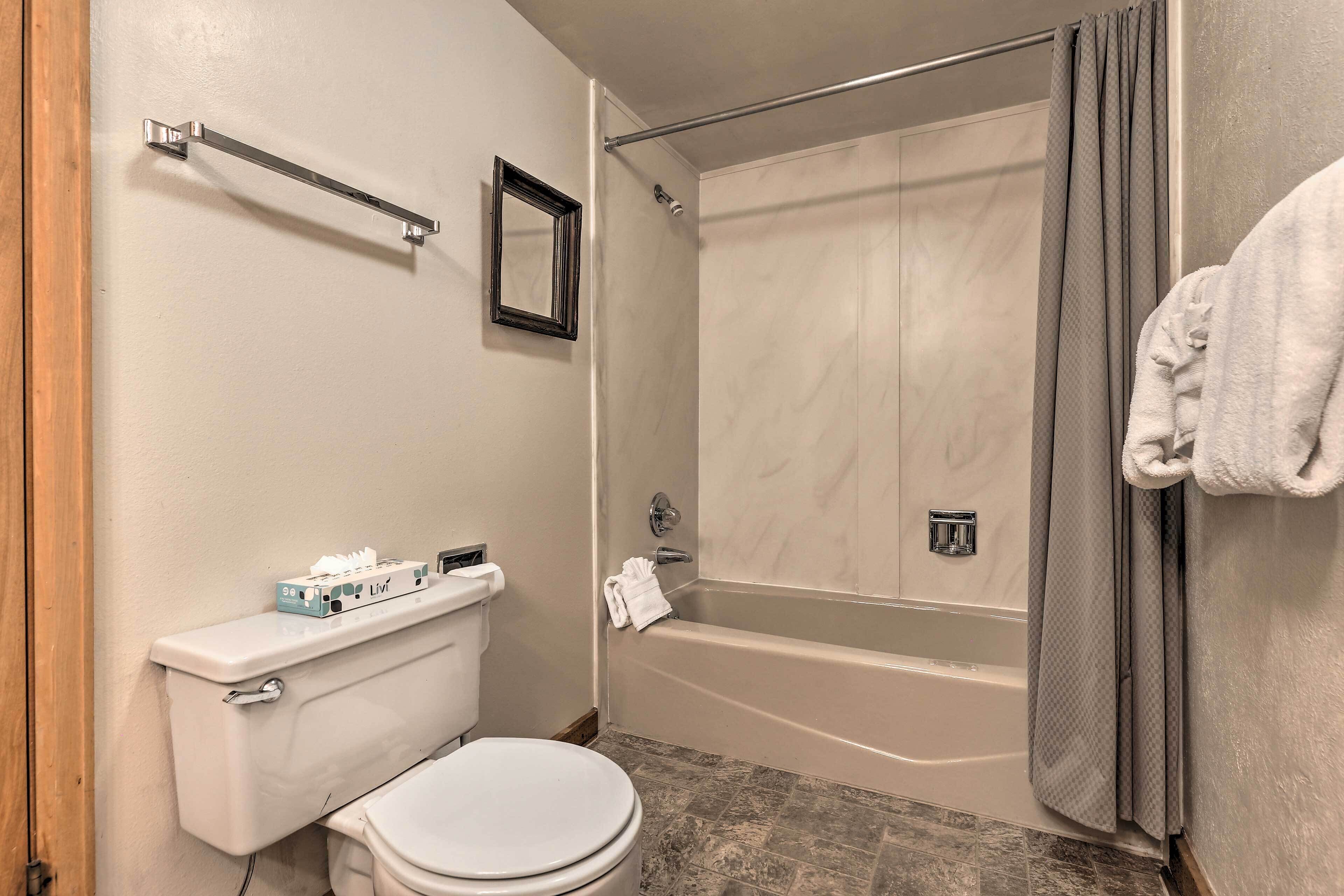 Een badkamer met toilet, bad en douche.