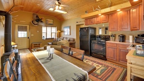 A spacious kitchen with wooden cabinets, a large dining table, and a ceiling fan.