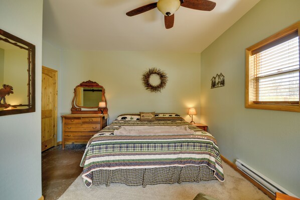 A bedroom with a bed, dresser, mirror, wall decorations, and a ceiling fan.