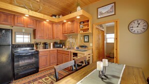 A kitchen with wooden cabinets, a black stove, and a dining area with a table and chairs.
