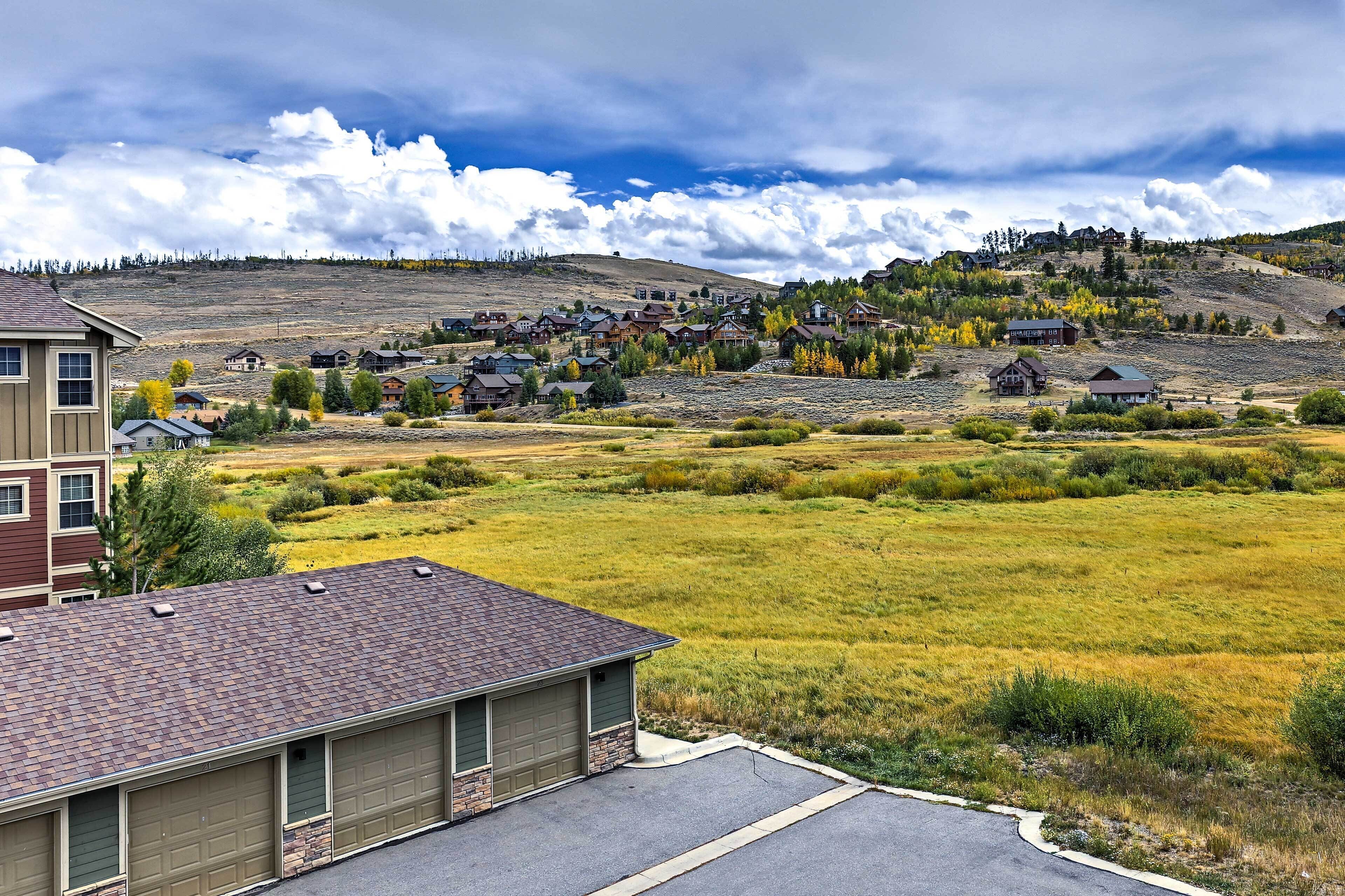A residential area with houses on a hillside, a clear sky, and a parking lot in the foreground.