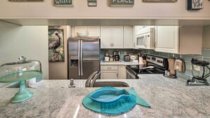 A kitchen with white cabinets, a stainless steel refrigerator, and a granite countertop.