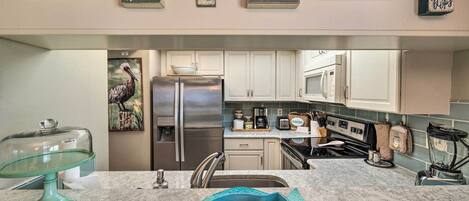 A kitchen with white cabinets, a stainless steel refrigerator, and a granite countertop.