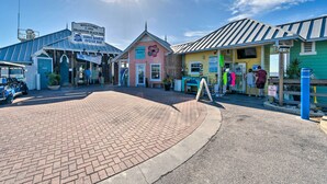 A coastal pier with a sign welcoming visitors to Bradenston Beach Pier, featuring a restaurant named Anna Maria Oyster Bar and a shop with a 'Hello' sign.