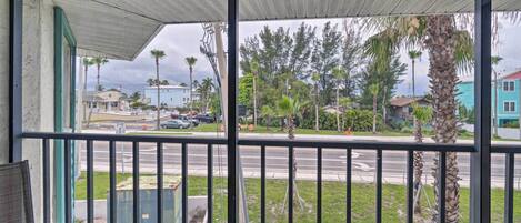 A balcony with a view of a street, palm trees, and buildings.