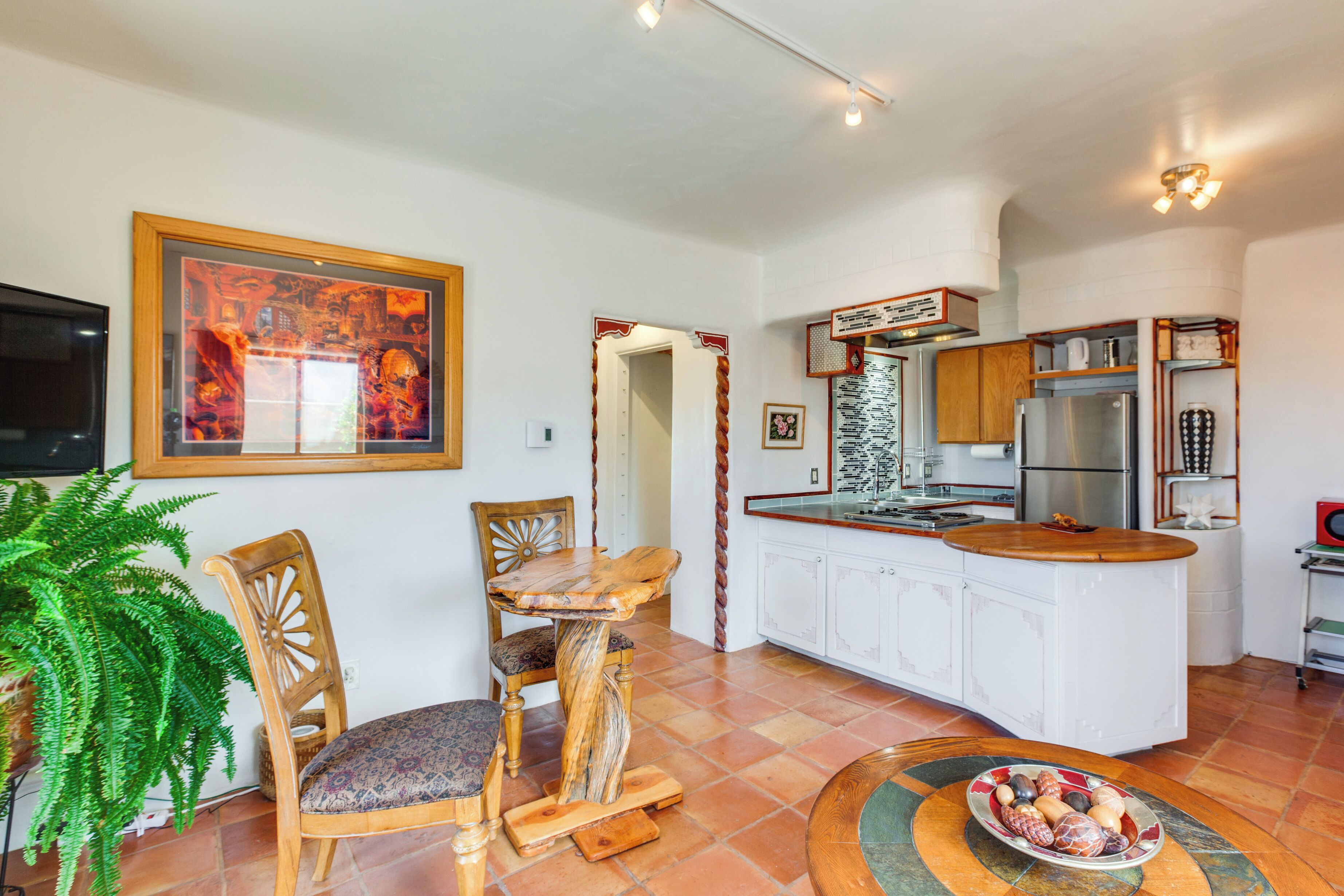 A modern kitchen with white cabinets, a wooden island, and a dining area with a table and chairs.