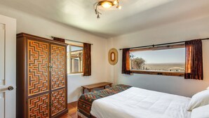 Een slaapkamer met een bed, een kledingkast, een ronde spiegel en een raam met gordijnen.