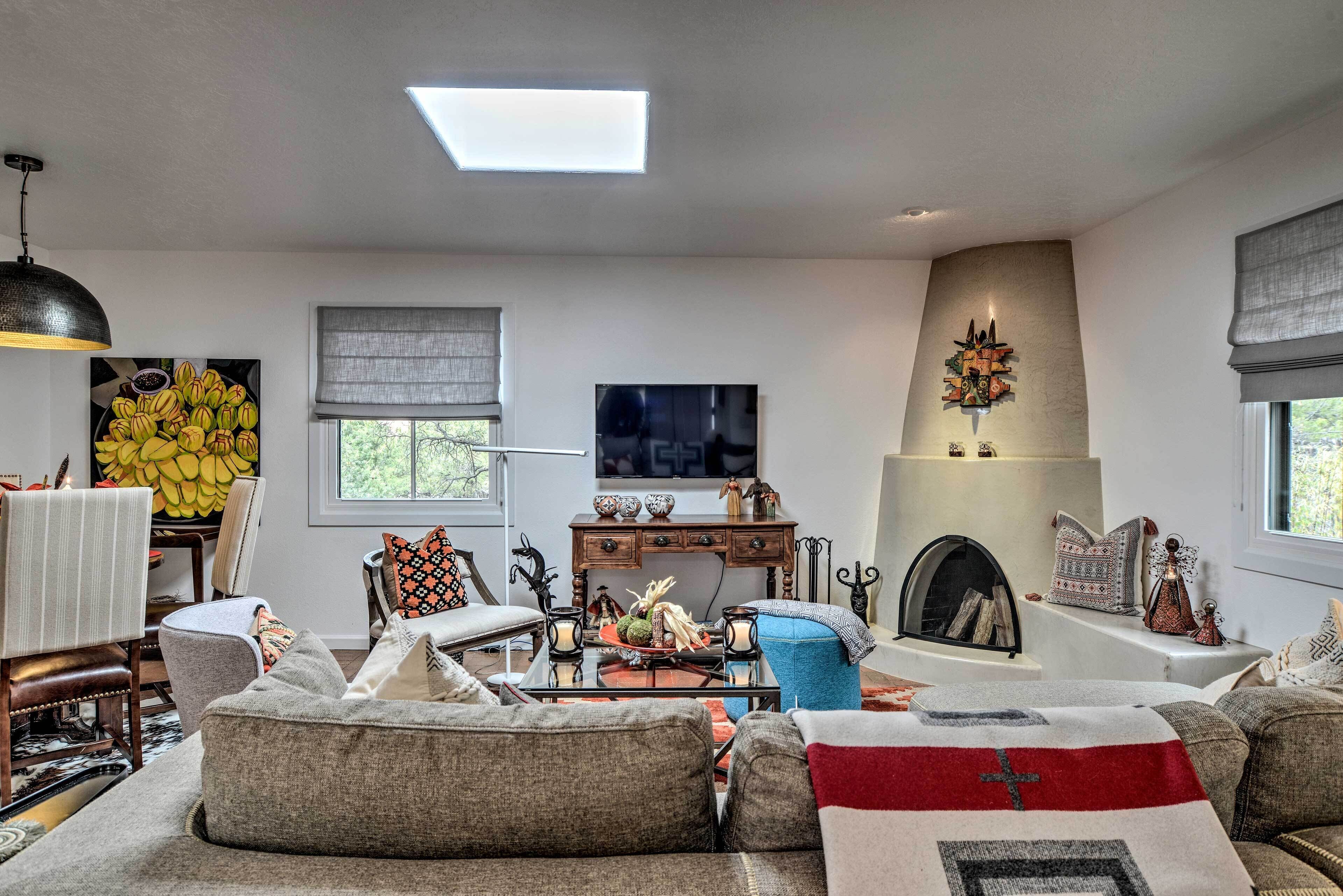A modern living room with a fireplace, comfortable seating, and a large window.