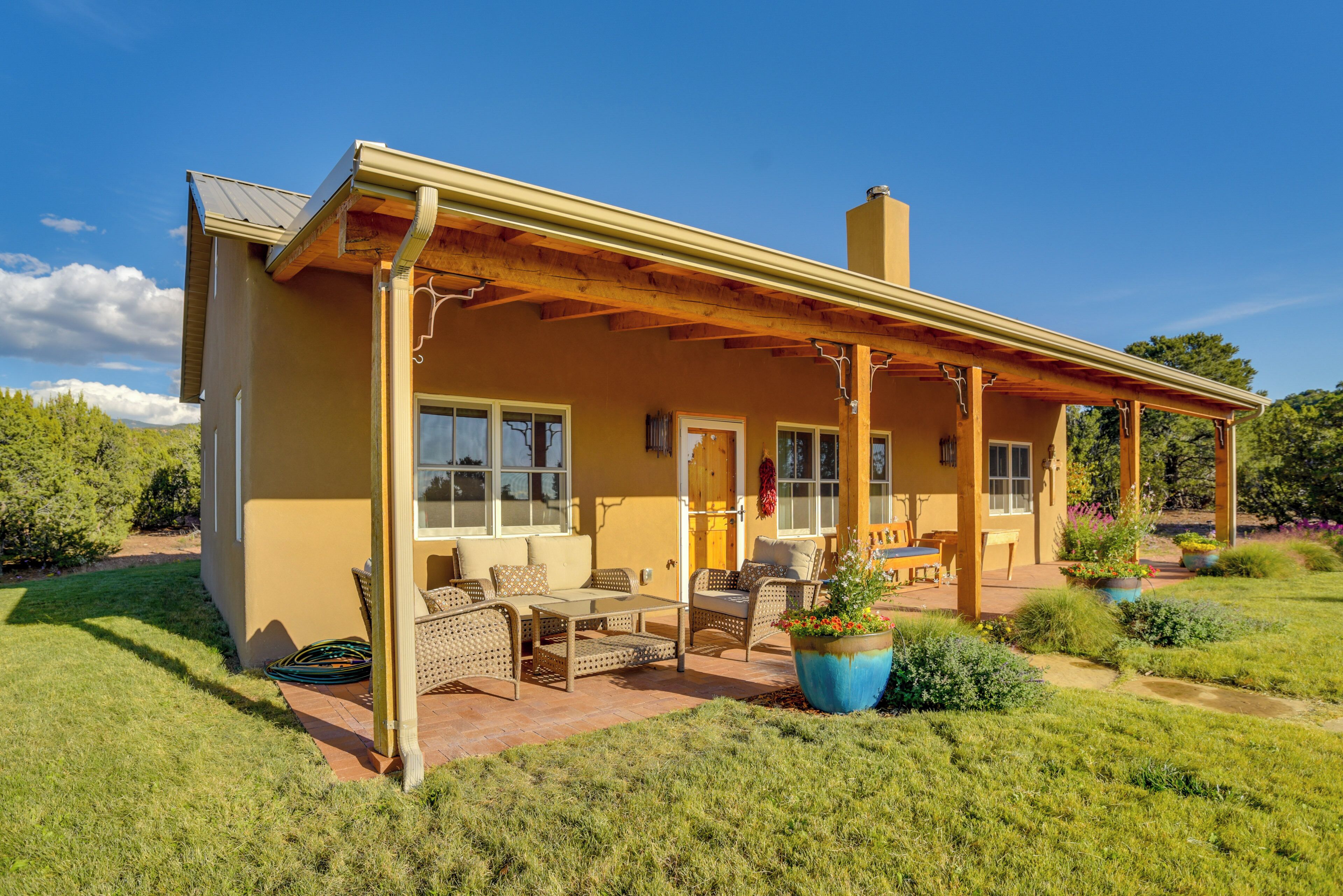 A single-story house with a covered patio, outdoor seating, and a garden.