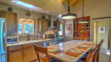 A modern kitchen with wooden cabinets, a large island, and a dining area set for six.