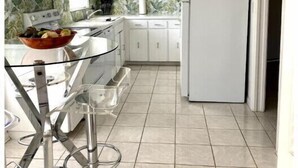 Una cocina moderna con armarios blancos, un refrigerador blanco y una barra con encimera de vidrio.