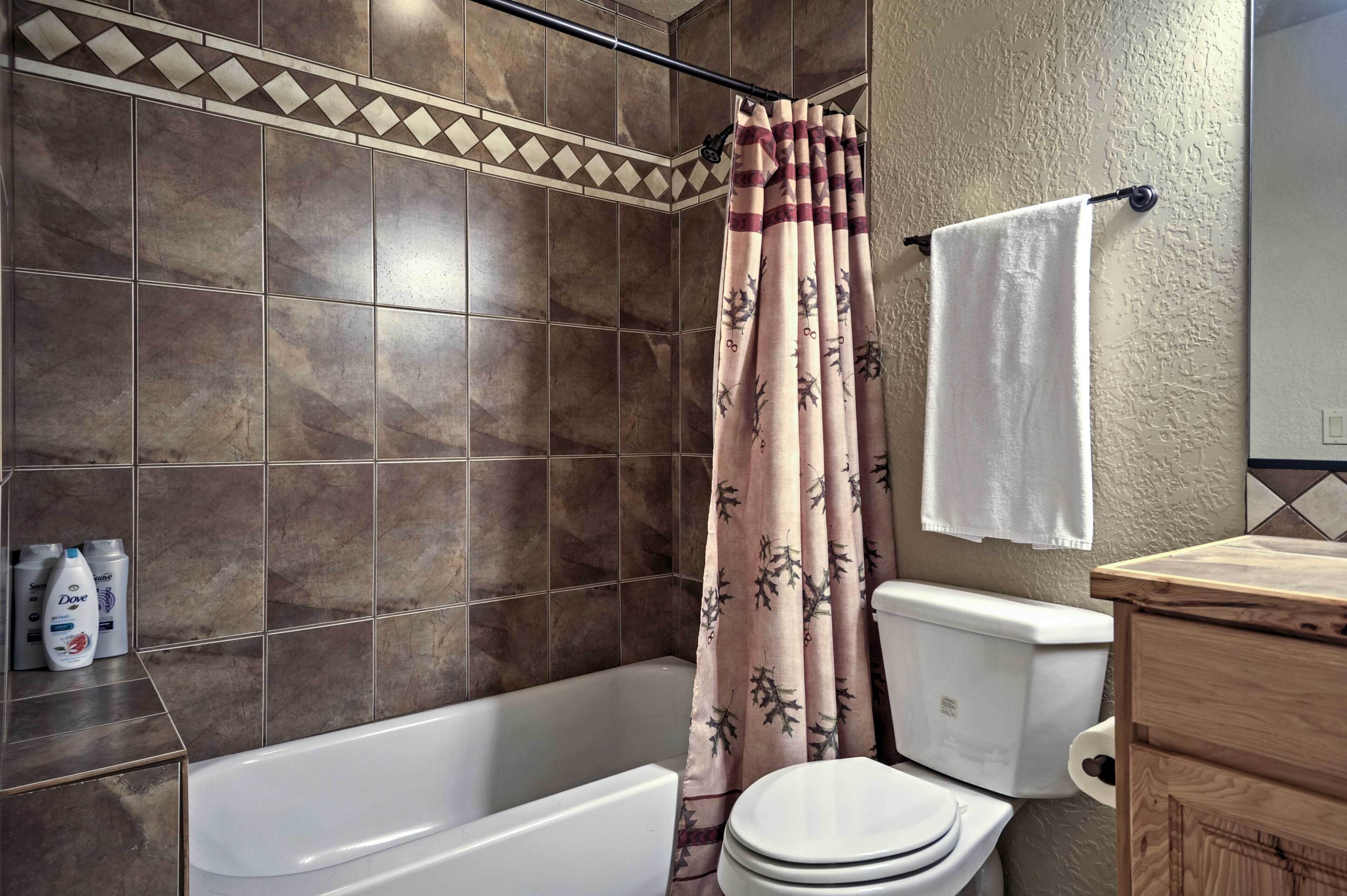 A bathroom with a bathtub, toilet, and shower curtain.