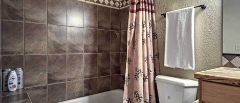 A bathroom with a bathtub, toilet, and shower curtain.