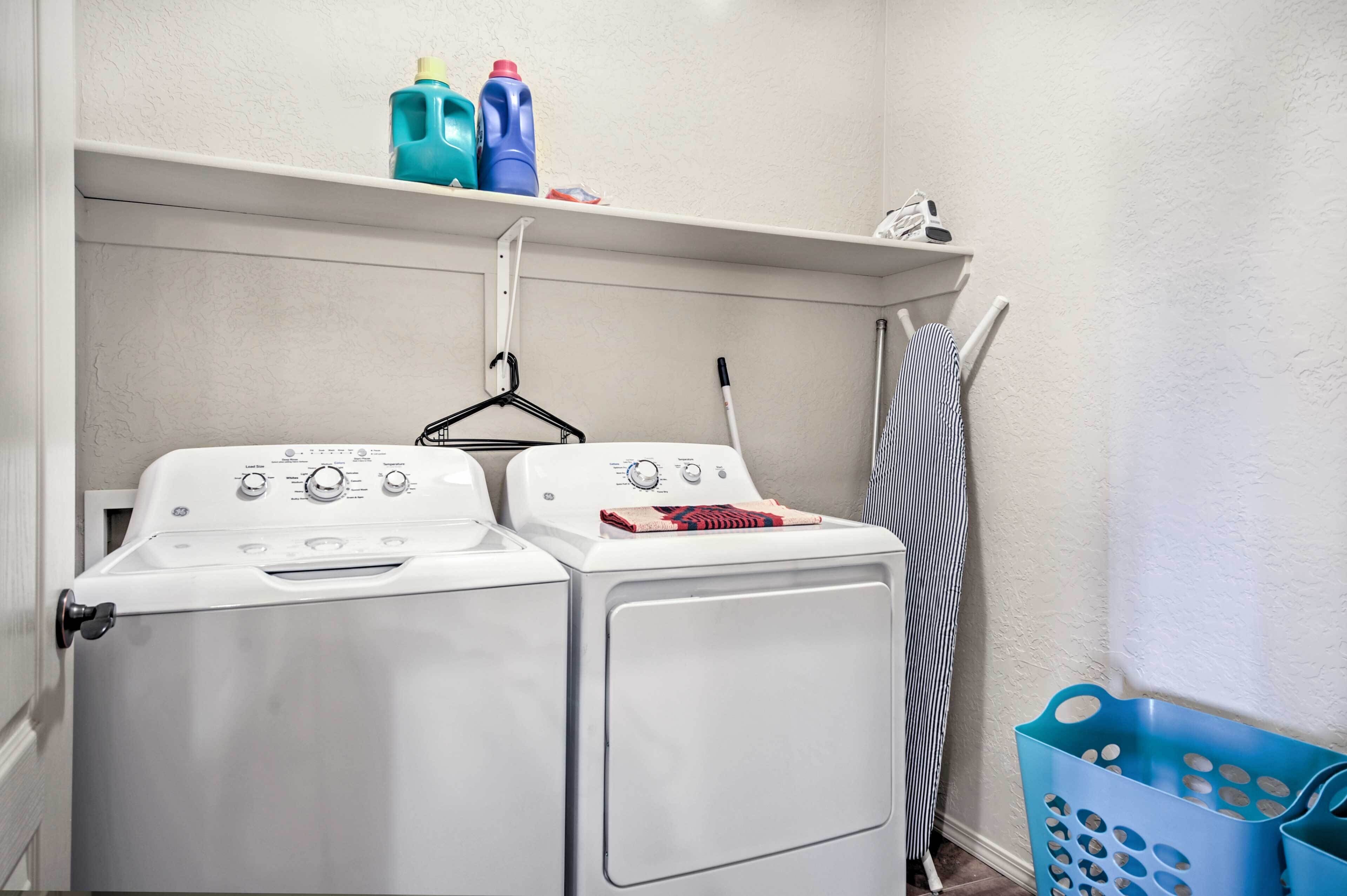 Een wasruimte met twee voorladers, een droogrek en een blauwe wasmand.