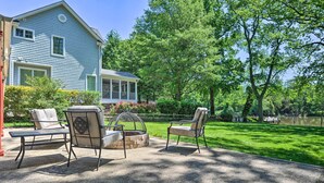 Une terrasse avec deux chaises et une table, un foyer en pierre et une vue sur un lac.