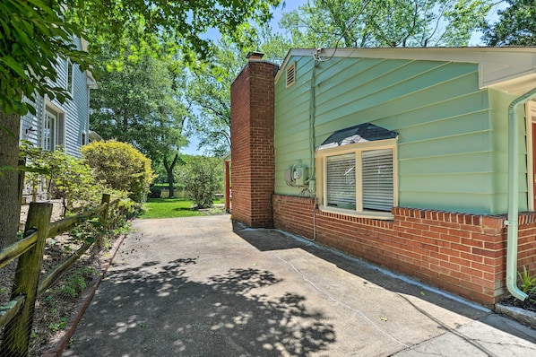 A residential property with a brick chimney, a green siding exterior, and a paved driveway.