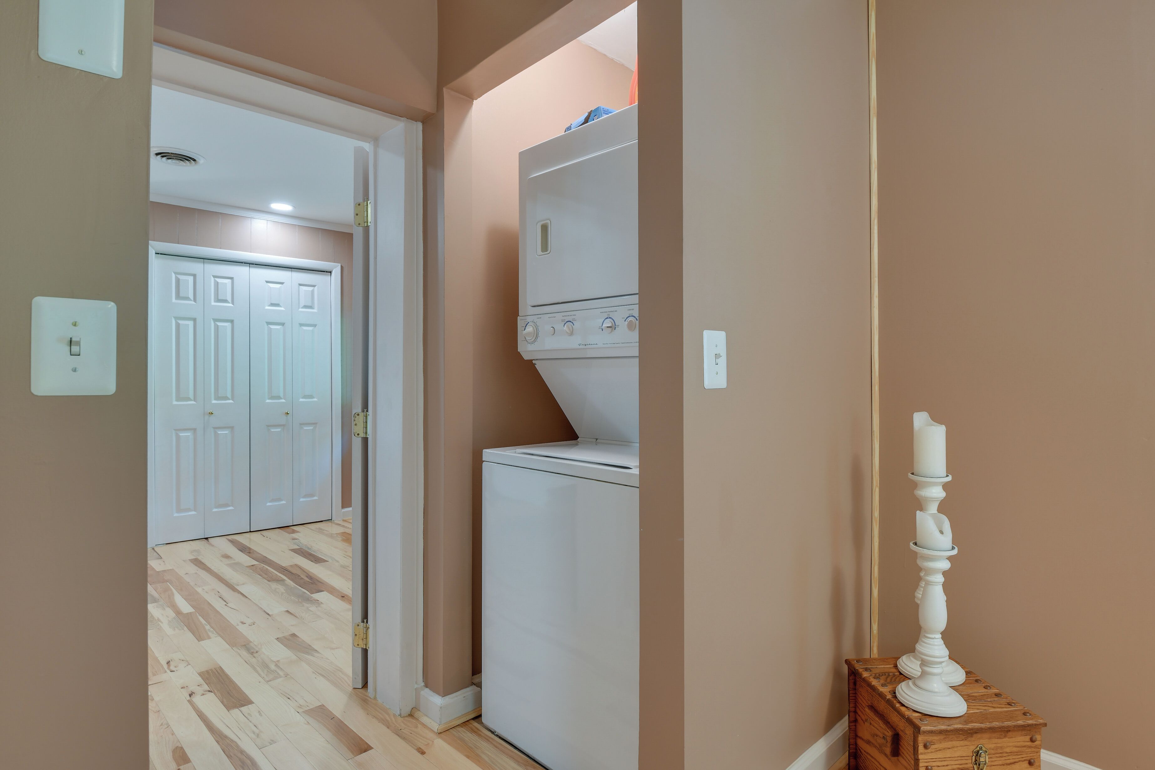 Une buanderie équipée d’un lave-linge et d’un sèche-linge, d’une commode en bois et, au fond, d’une porte blanche.