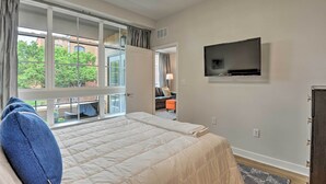 A bedroom with a large bed, a TV mounted on the wall, and a view of the outdoors through a sliding door. - Chic Condo w/ Balcony in the Heart of Annapolis! (Annapolis)