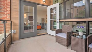 An open door leading to a living area with wicker furniture and a glass table. - Chic Condo w/ Balcony in the Heart of Annapolis! (Annapolis)