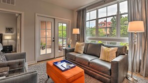 A living room with a leather sofa, a coffee table, and a large window with curtains. - Chic Condo w/ Balcony in the Heart of Annapolis! (Annapolis)