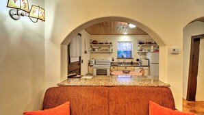 A cozy living room with a sofa and a kitchen in the background. - Charming Couples Casita, Walk to Old Mesilla Plaza (Mesilla)