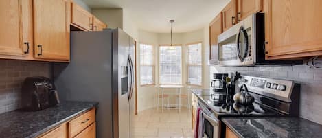A kitchen with wooden cabinets, a refrigerator, a microwave, a stove, and a coffee maker.