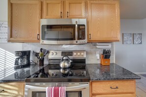 A kitchen with wooden cabinets, a stainless steel microwave, a gas stove, and a coffee maker. - Updated Springs Home - 3 Mi to Garden of the Gods! (Colorado Springs)