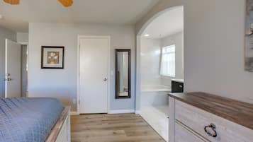 Quarto com cama, penteadeira, espelho e porta.
