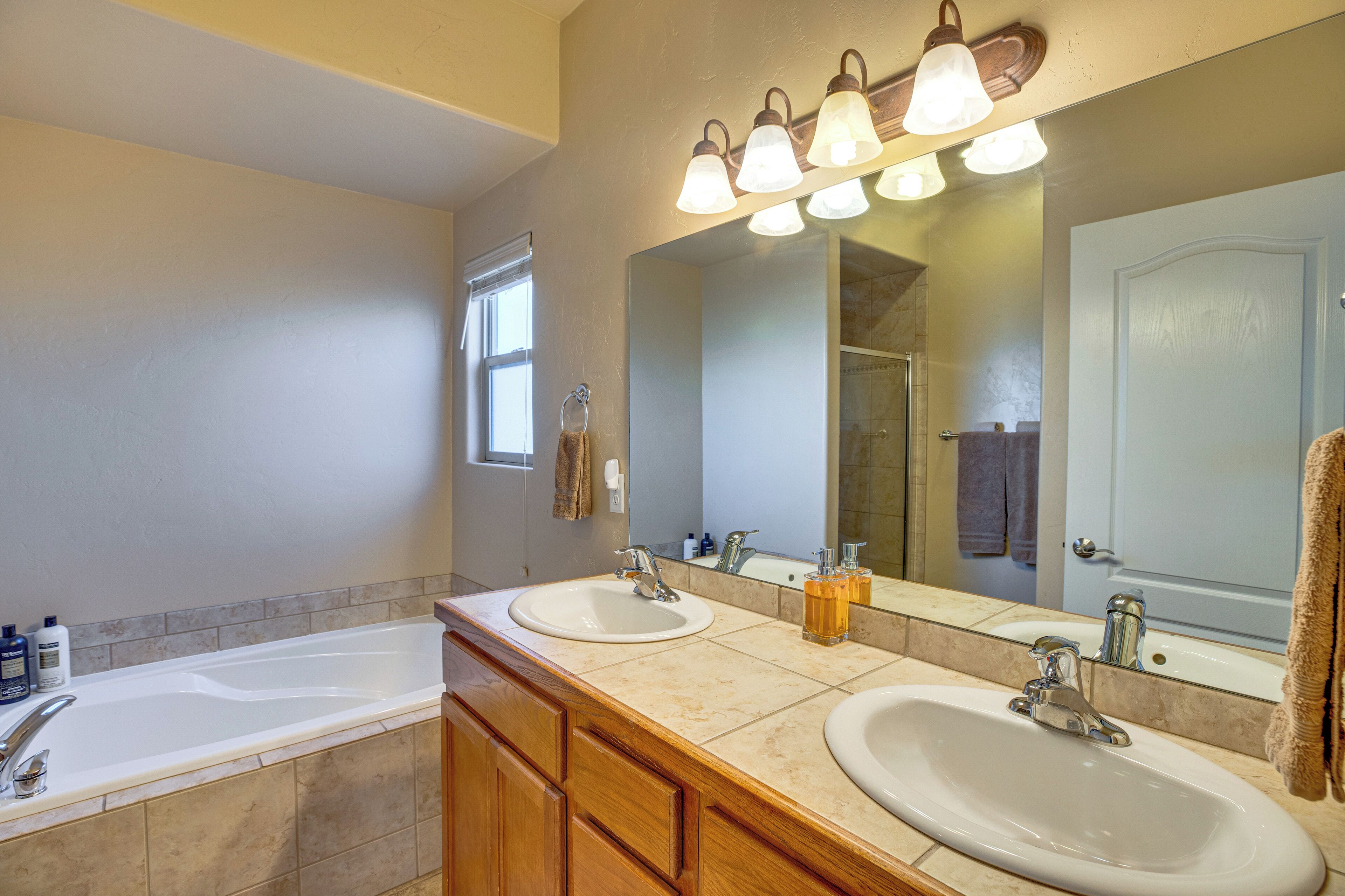 A bathroom with two sinks, a bathtub, and a large mirror.